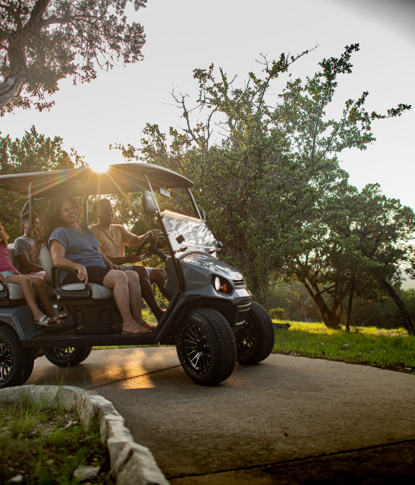 People riding golf cart at sunset